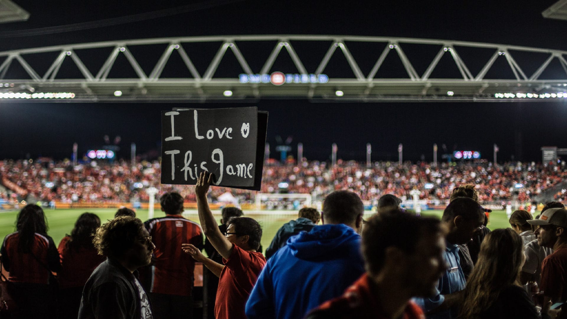 I love this game placard held by person in the stadium